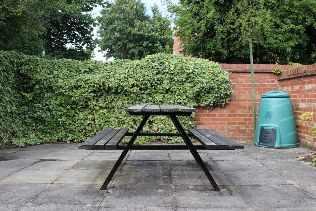 Green yard with red brick walls and wood table bench