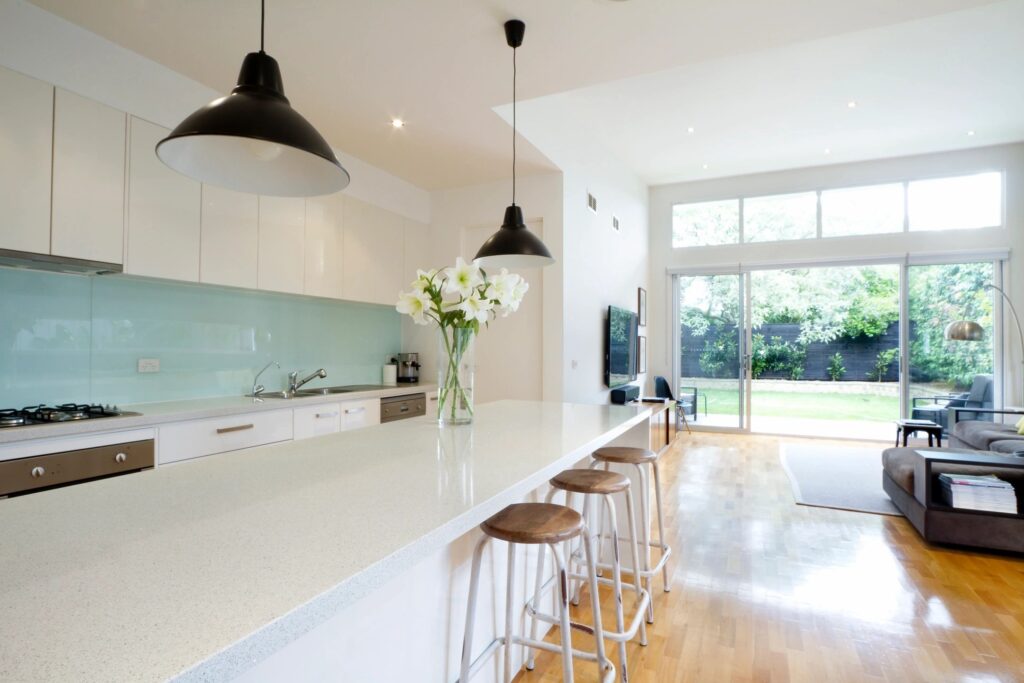 Minimalist white interior kitchen with light teal backsplash and wooden floor - open plan design with lots of natural light